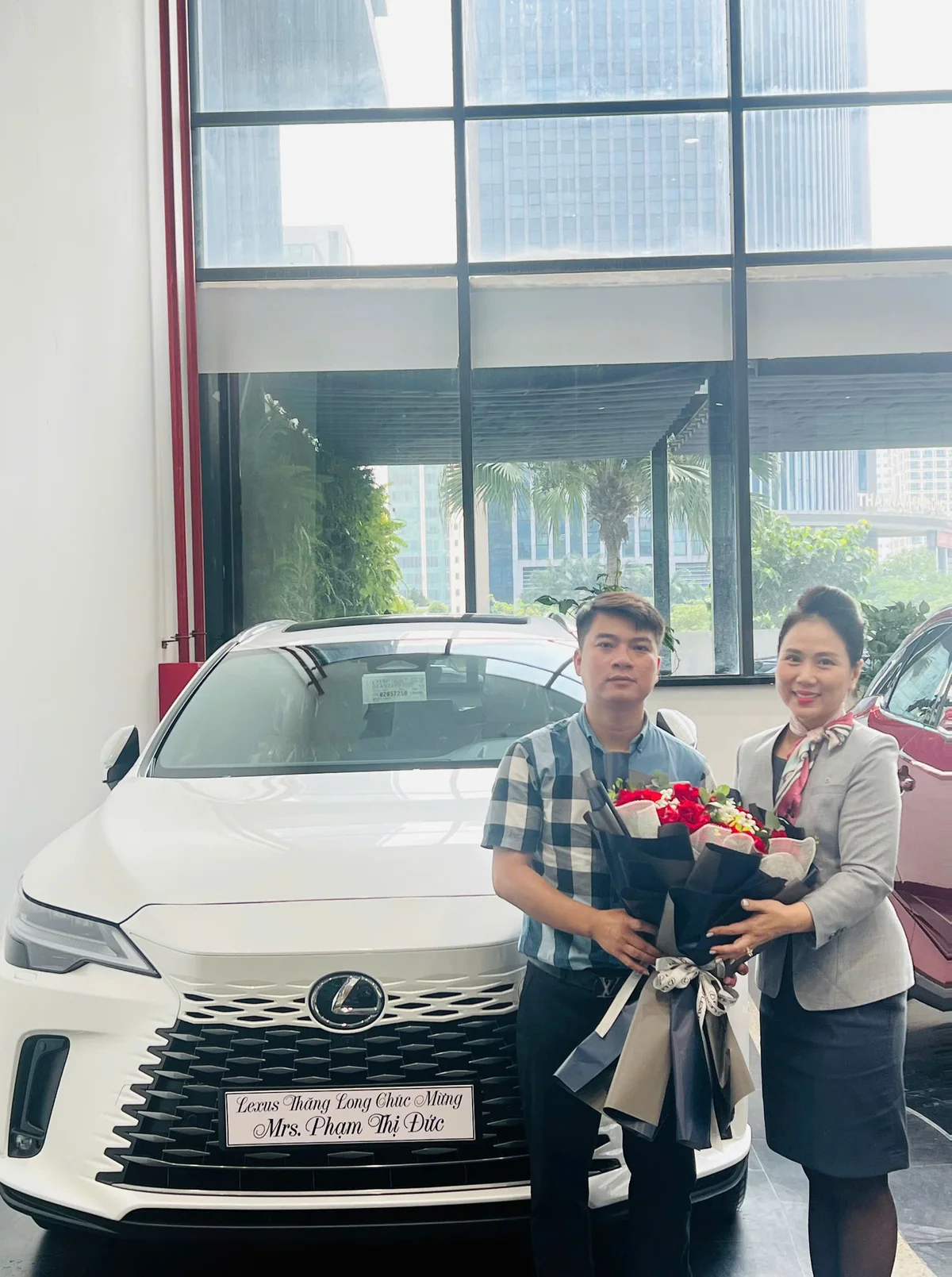 Chuyên viên và khách hàng cầm hoa bên chiếc Lexus màu trắng